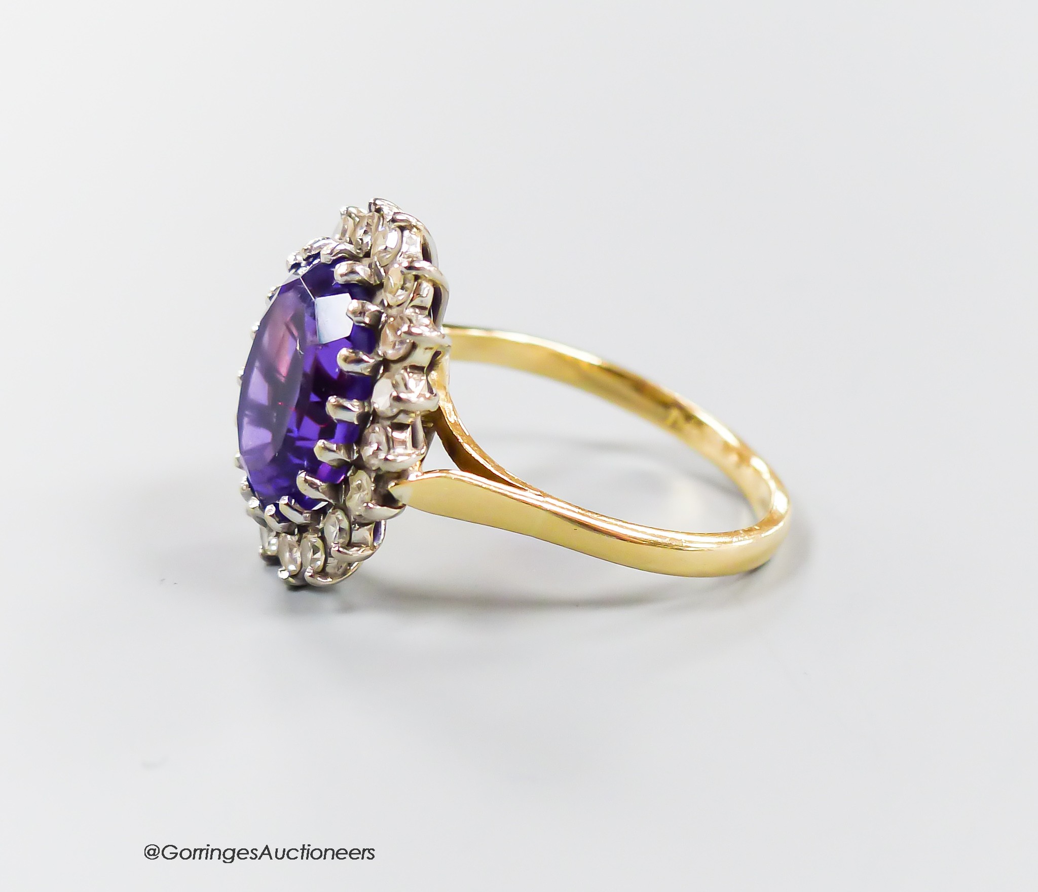 A modern yellow metal, amethyst and diamond set oval cluster ring, size O, gross 5.6 grams.